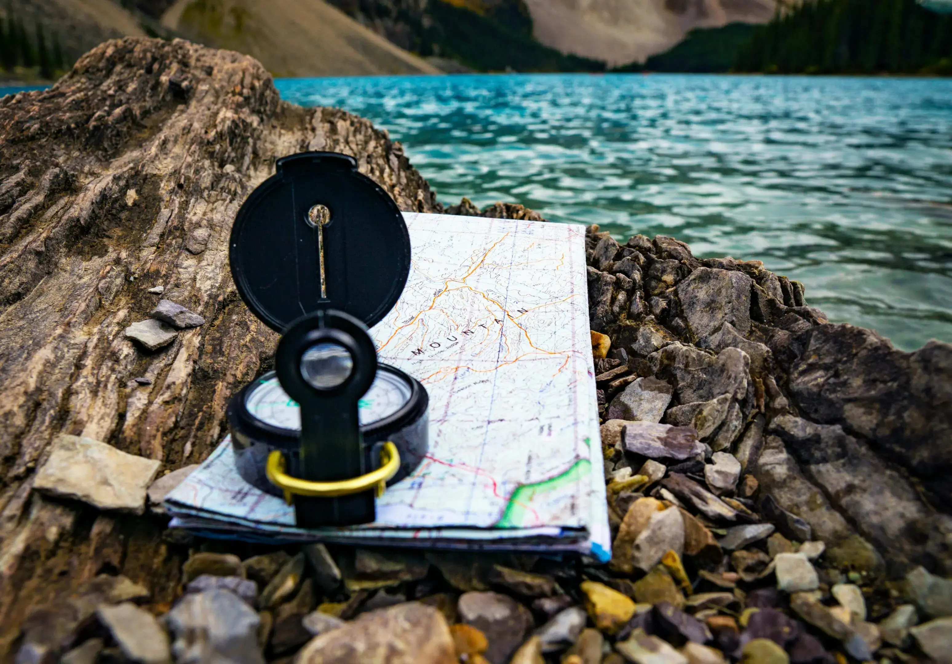 Compass and map on rocky shore.